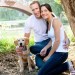 a couple kneeing next to their dog on a trail